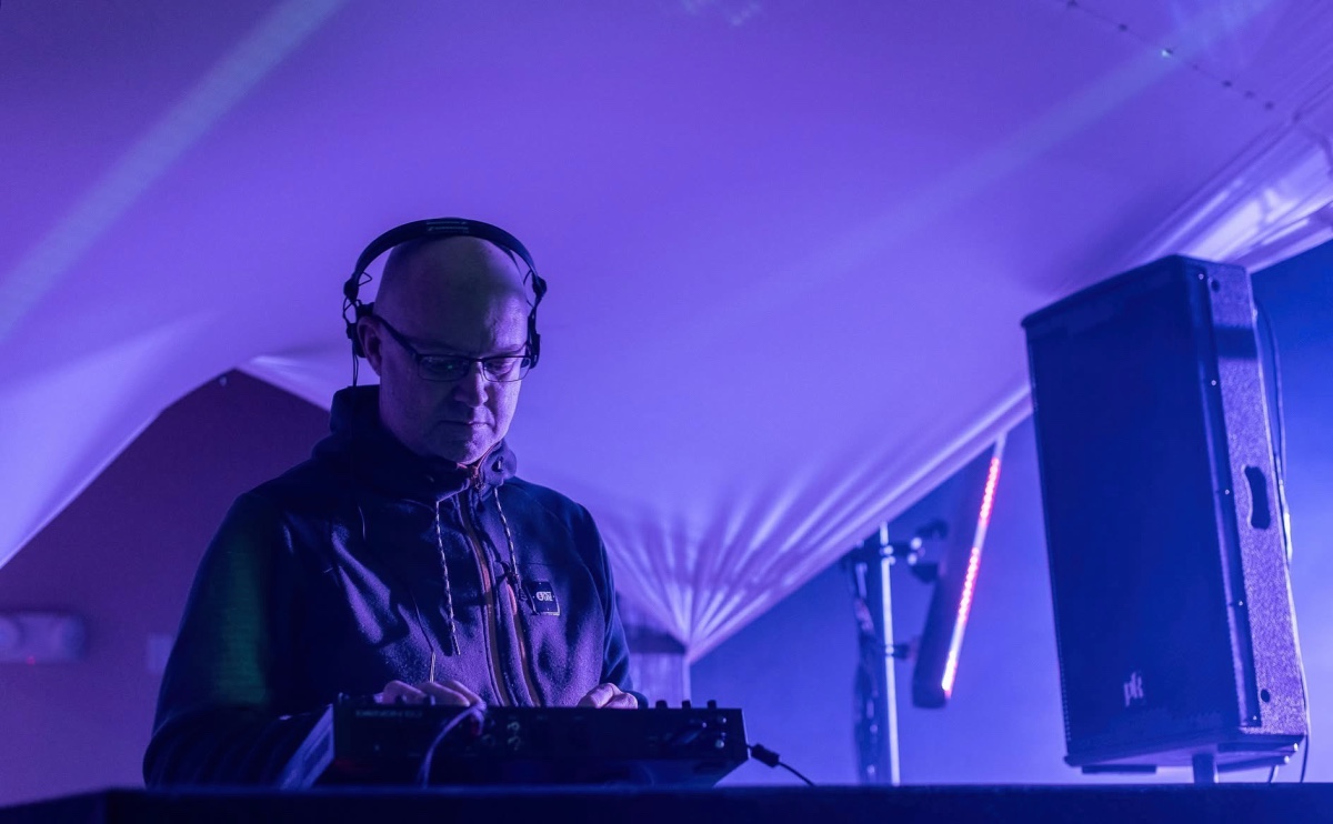 Man with headphones on DJing under tent 